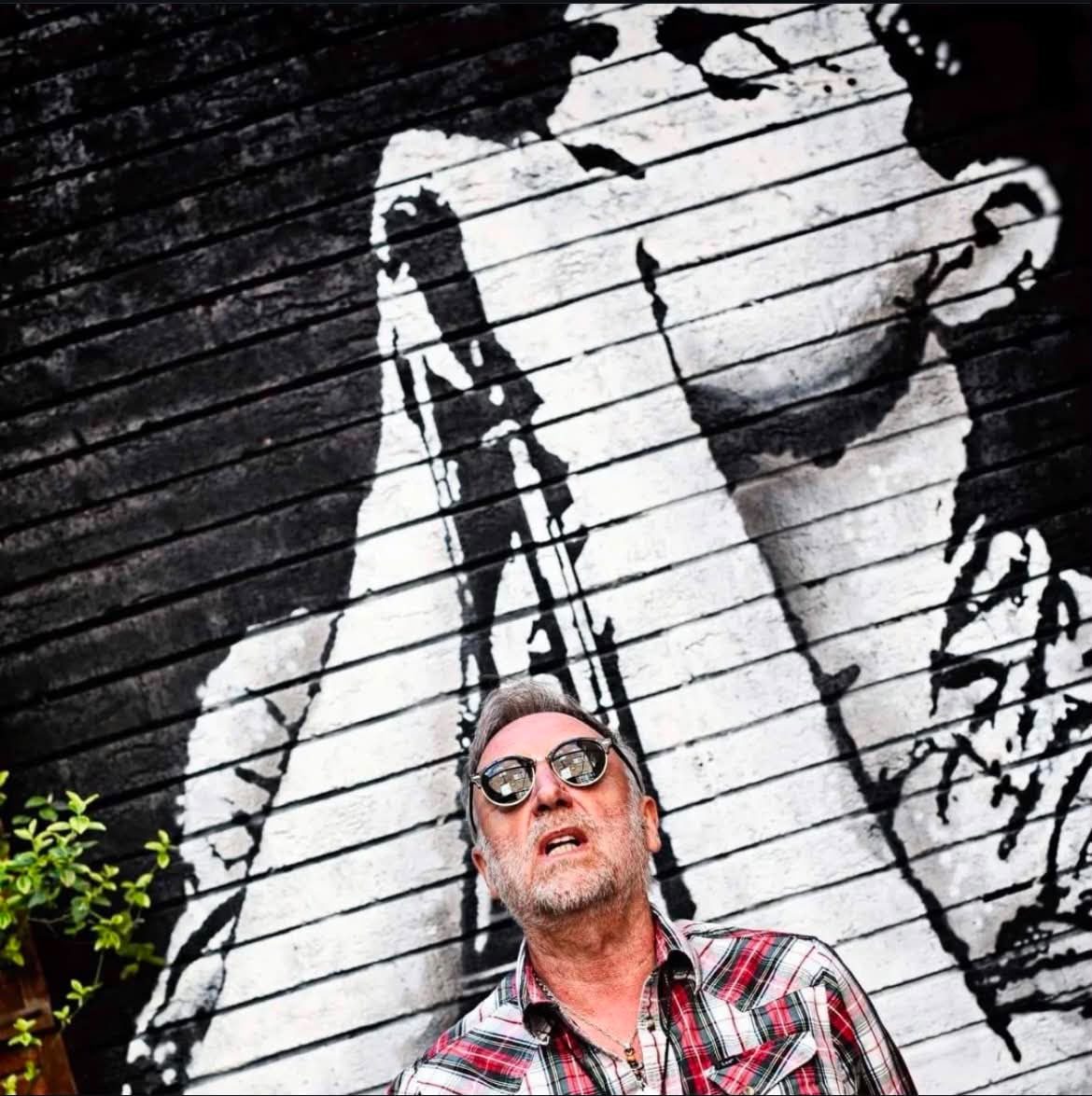 A visitor standing in front of the Ian Curtis mural in the Proper Sound courtyard